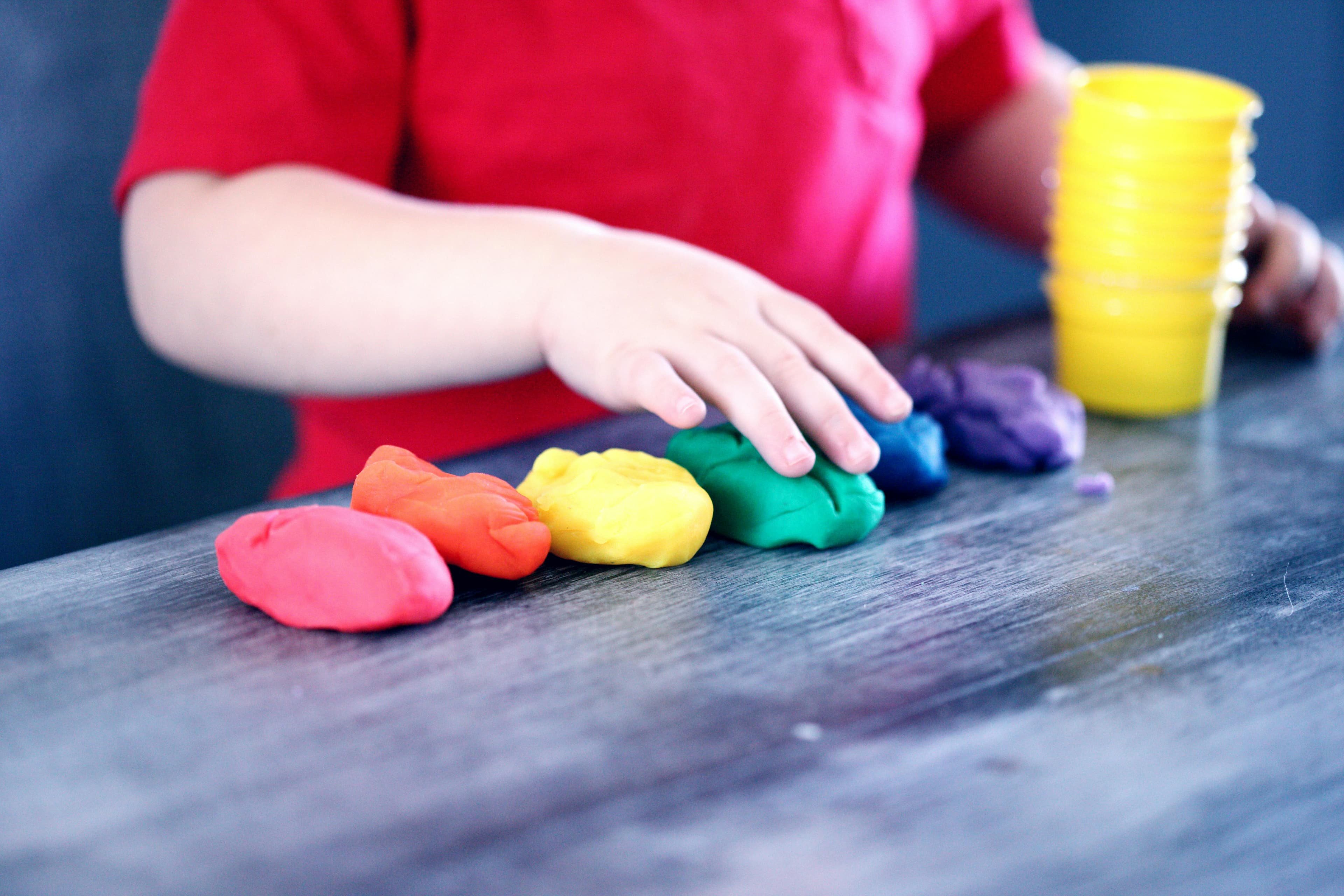 A child's hands with multiple lumps of differently colored clay.